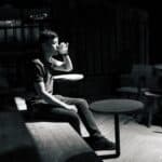 Bărbat singur care bea noaptea într-un bar slab luminat, fotografie alb-negru