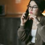 Femeie îngrijorată care vorbește la telefon seara, acasă
