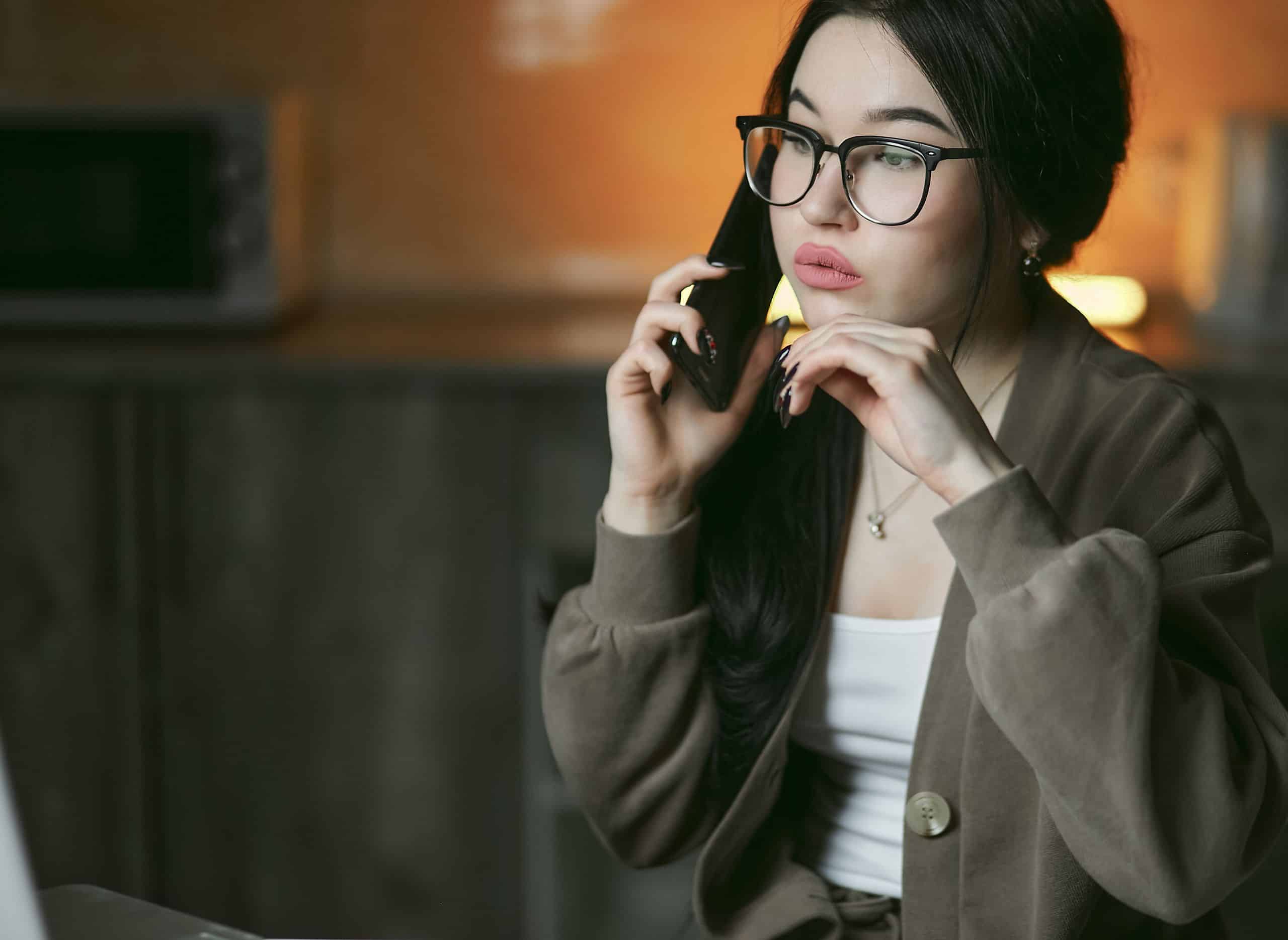 Femeie îngrijorată care vorbește la telefon seara, acasă