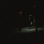 Un om merge singur noaptea pe o stradă întunecată, sub lumina unui felinar