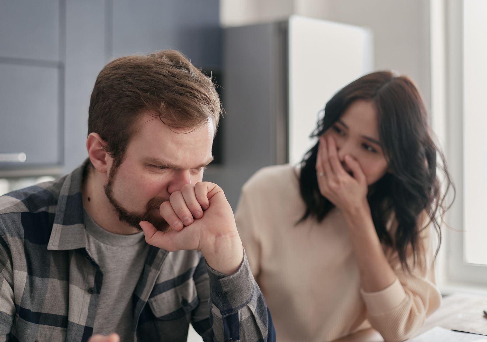 Bărbat îngrijorat stă lângă partenera lui, într-o discuție serioasă acasă